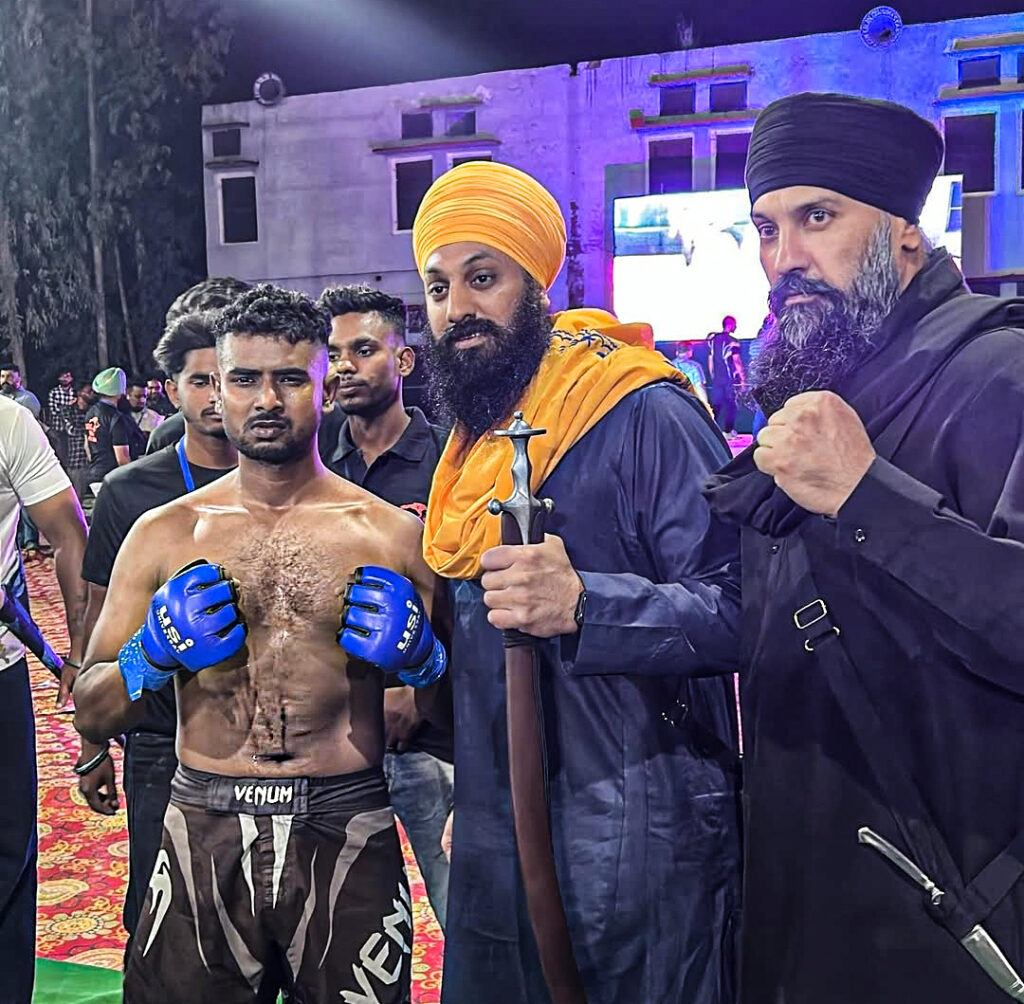 A professional boxer Jaspreet Singh standing confidently in the right side wearing boxing gloves and with their coaching team and cornermen.